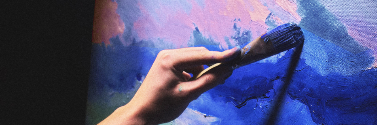 Hand med pensel som målar en tavla. Käsi siveltimellä maalaamassa taulua.