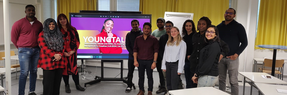 Människor framför en skärm. Ihmisiä näytön edessä.